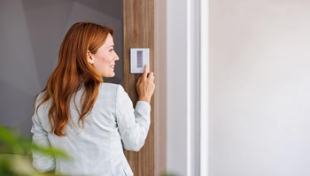 Mulher jovem em casa regula termostato inteligente